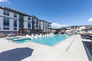 a swimming pool with lounge chairs in front of an apartment building
